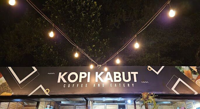 Pengunjung sedang menikmati kopi dengan latar belakang kabut dan pegunungan di Kopi Kabut Sevillage.